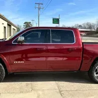Red pickup truck parked on a concrete driveway beside a building under a clear sky.