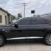 Black SUV parked outdoors beside a building under an overcast sky