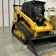 Yellow skid steer loader with bucket on a warehouse floor