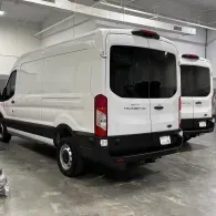 White cargo van parked in an indoor garage, rear three-quarter view.