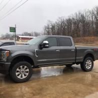 Gray pickup truck parked on a wet lot under an overcast sky