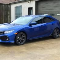 Blue sports sedan parked in a driveway in front of a garage