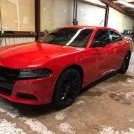 Red sports coupe parked indoors, viewed from the front-left side.