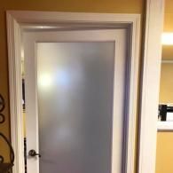 Frosted glass interior door with a dark doorknob in a hallway opening.