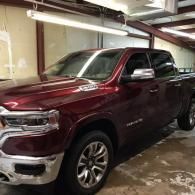 Maroon pickup truck parked in a garage, front-left view, with chrome trim and wet floor.