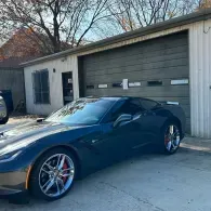 Dark blue sports car parked in front of a garage with a closed door