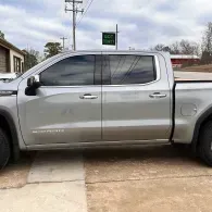 Silver pickup truck parked in a driveway beside a house, side view