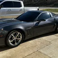 Black sports car parked in a driveway beside a silver pickup truck