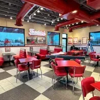 Retro diner interior with red booths, red chairs, checkered floor, and wall-mounted TVs