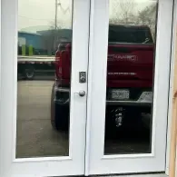 Red pickup truck seen through glass double doors in a parking lot