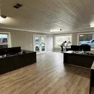 Bright office lobby with wood floors, desks, large windows, and a glass door