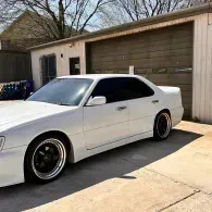 White coupe parked in a driveway in front of a garage