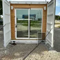 Open shipping container with glass double doors and concrete steps outside