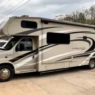 White Leprechaun motorhome parked in a driveway, side view