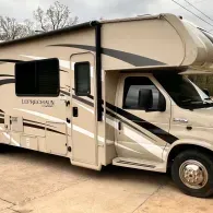 Beige Coachmen Leprechaun RV parked in a driveway