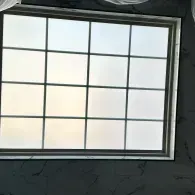 White-paned window with a grid of panes set in a dark wall.