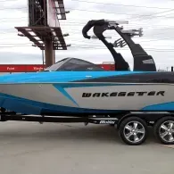 Blue-and-silver boat on a trailer with a black wakeboard tower and chrome wheels
