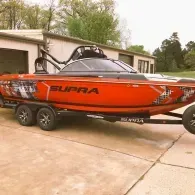 Orange Supra wakeboat on a trailer in a driveway
