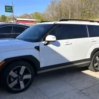 White SUV parked outdoors in a lot, side view with tinted windows and black wheels