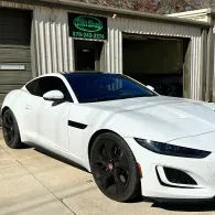 White sports coupe parked outside a garage with black wheels and tinted windows
