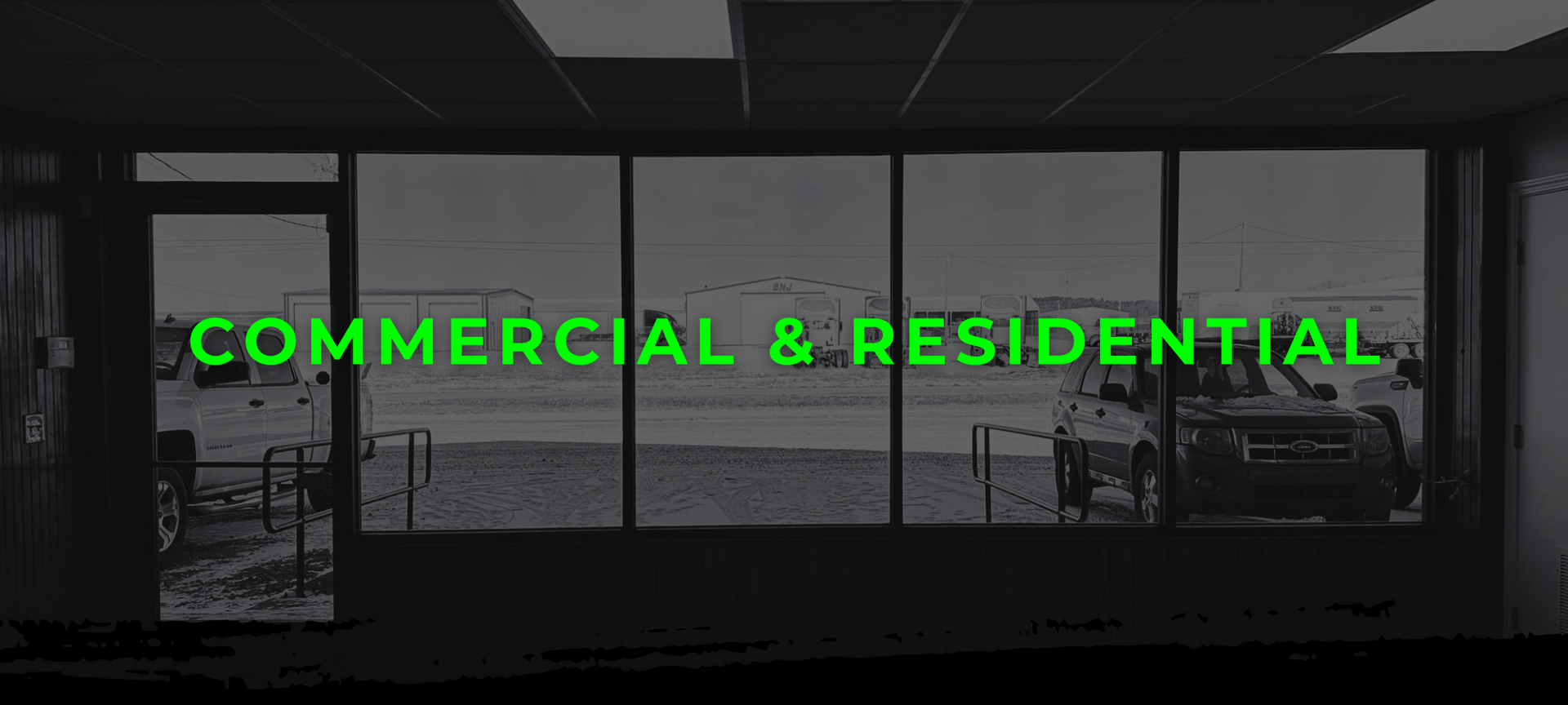 Commercial & residential property storefront with bright green text over a dark glass facade