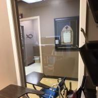 Office hallway with open door, wall window, and framed sign on the far wall.