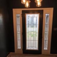 Front door with frosted glass panels and sidelights, illuminated by warm lights indoors