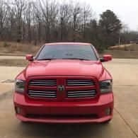 Red Dodge pickup truck parked on a driveway with bare trees in the background