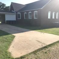 Brick house with a concrete driveway and green lawn in bright sunlight