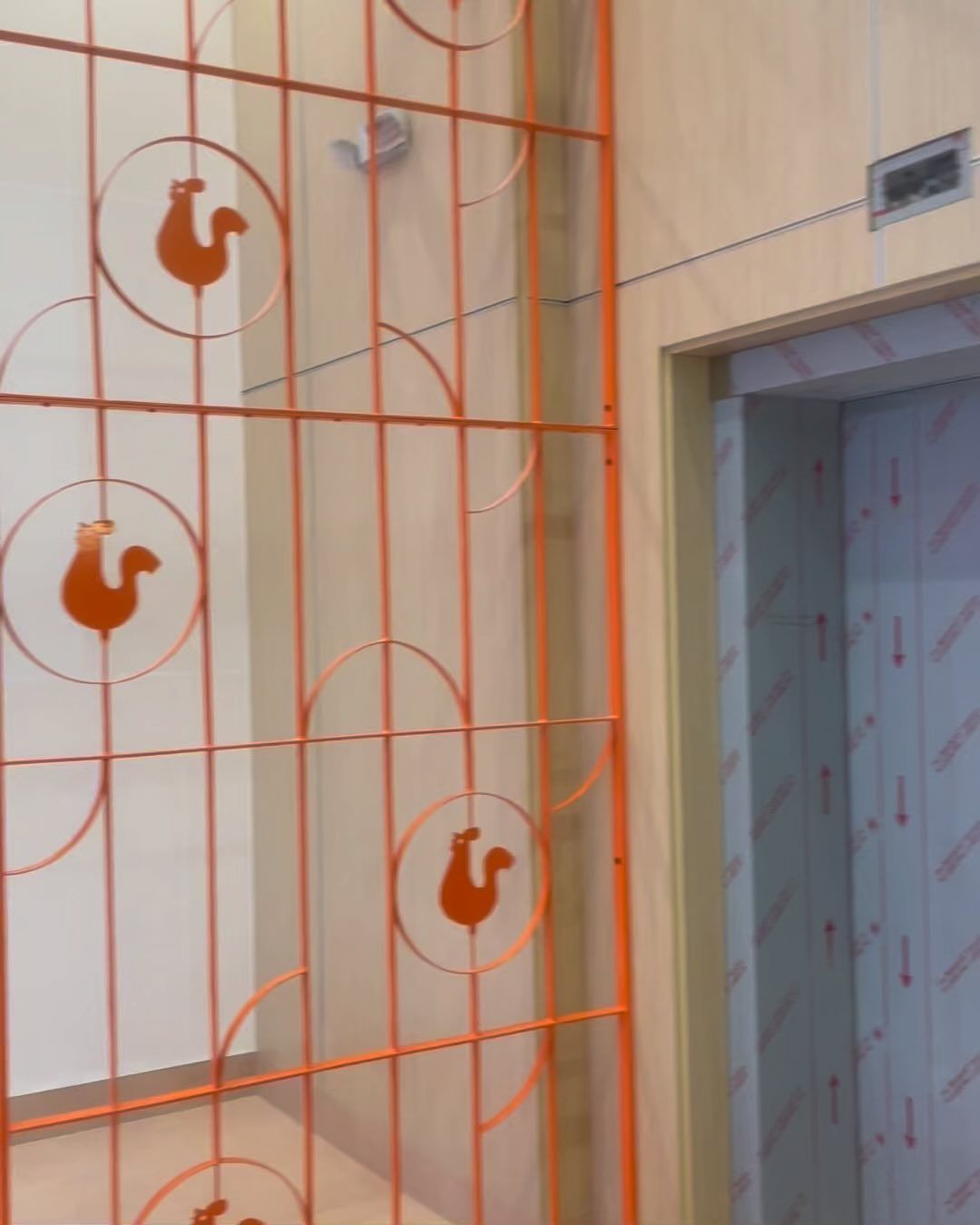 A squirrel is painted on an orange fence in front of an elevator