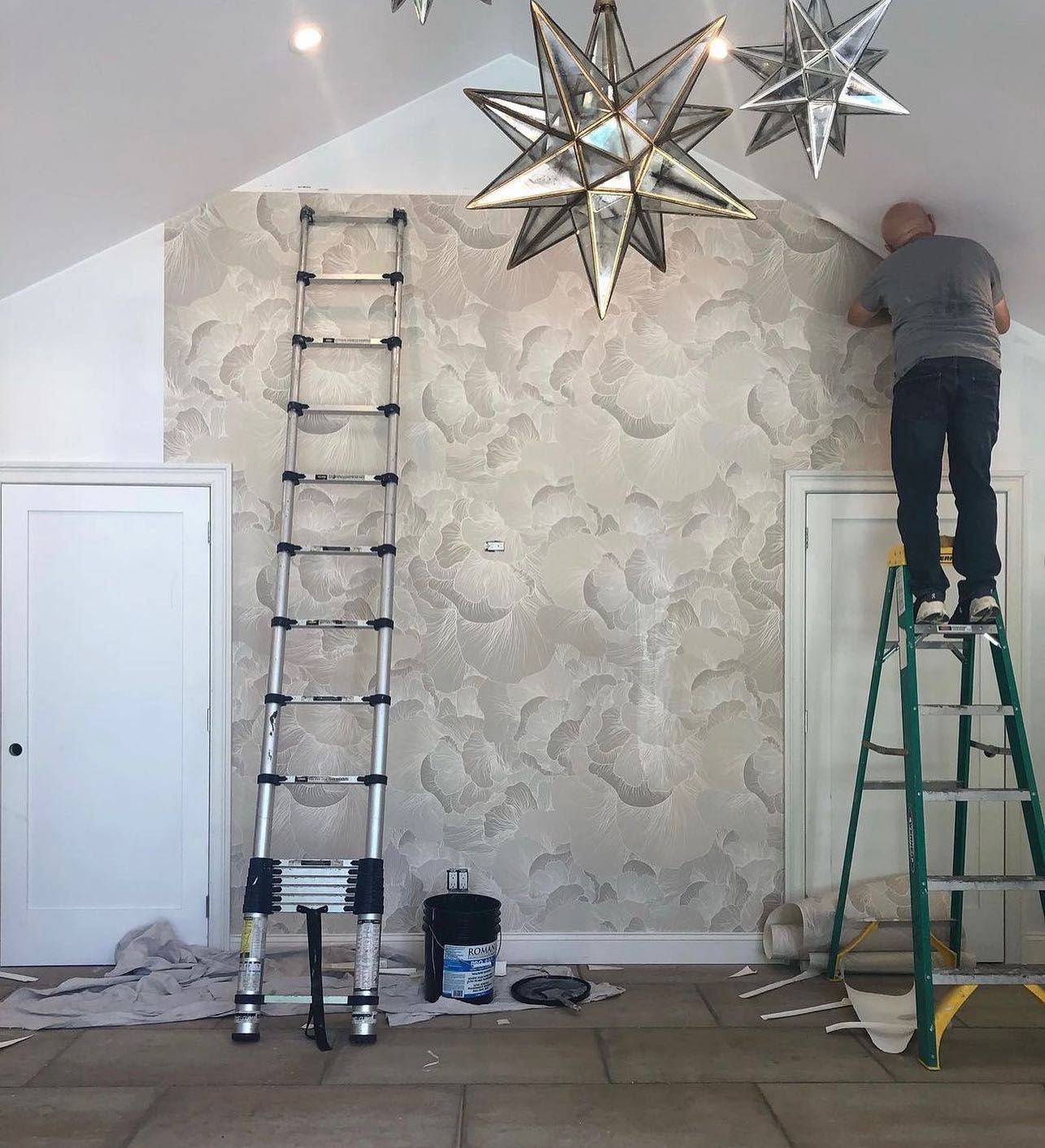 A man is standing on a ladder painting a wall