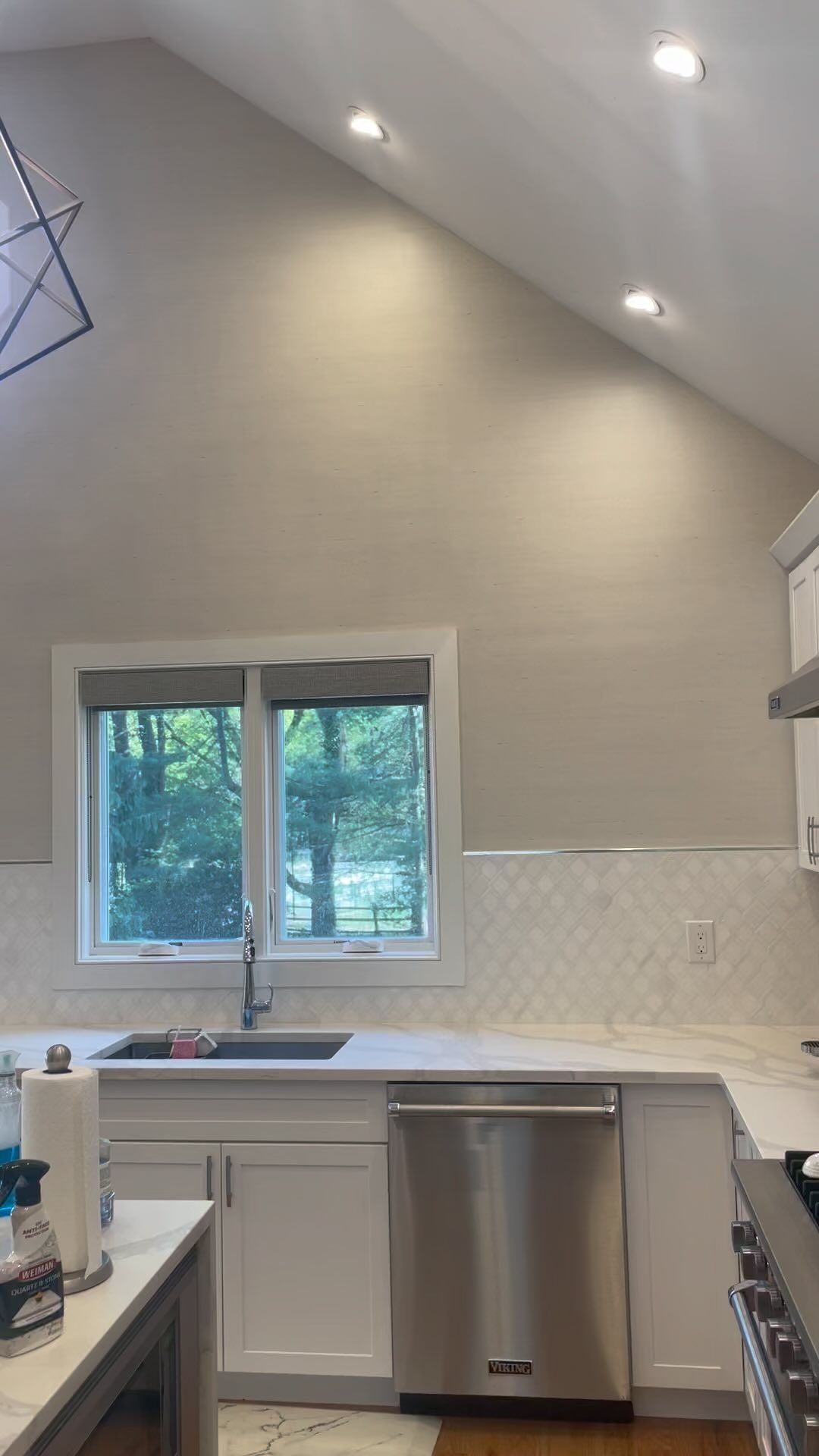 A kitchen with white cabinets , stainless steel appliances , a sink and a window.