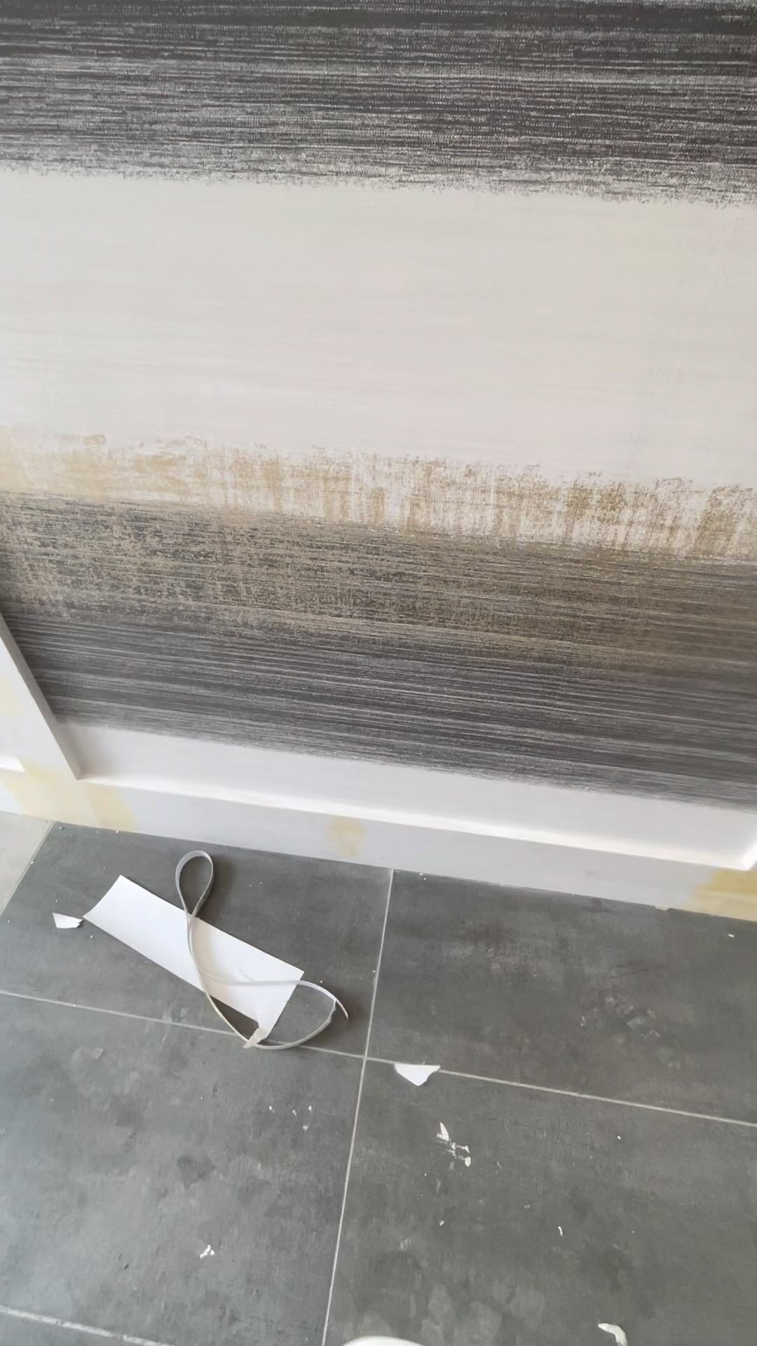 A piece of wallpaper is laying on the floor next to a wall.