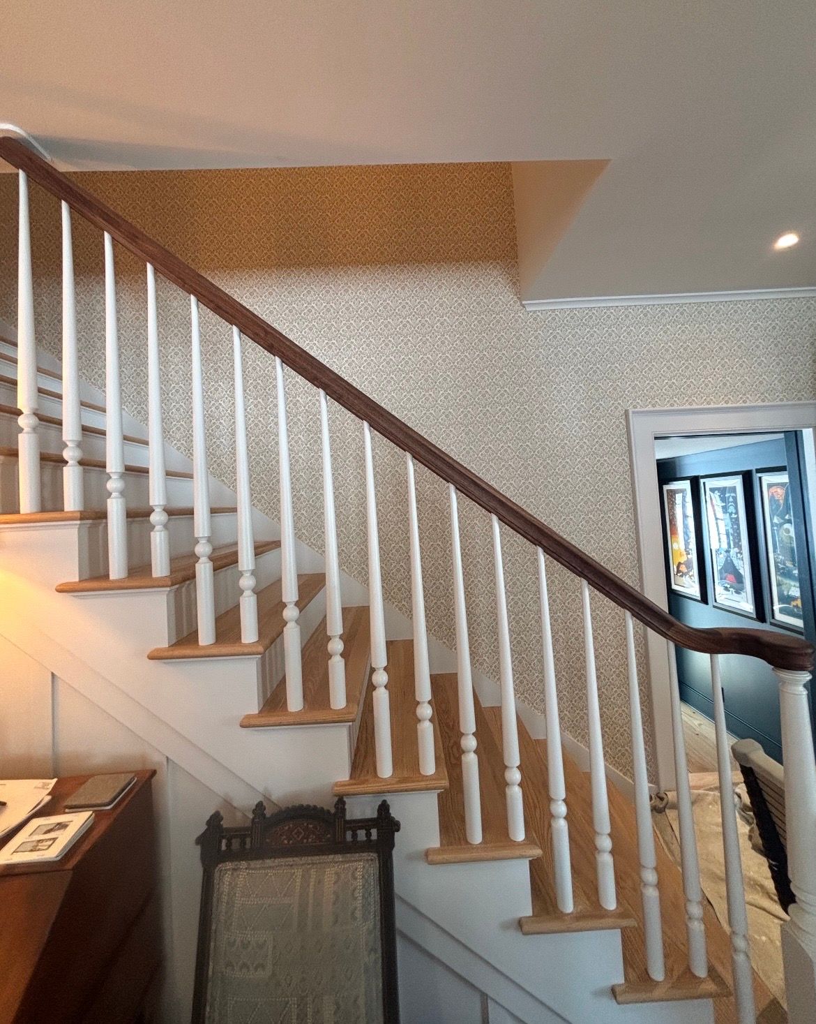 A room with hardwood floors and a window with a patterned wallpaper on the wall.