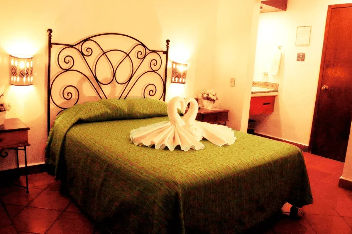 Una acogedora habitación de hotel con una cama con una colcha estampada en verde,
