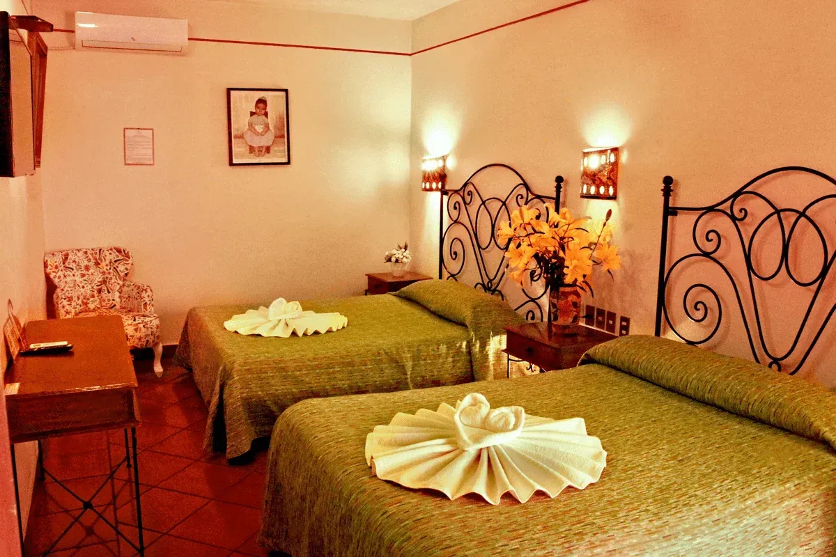 Un dormitorio con dos camas, decorado con colchas de estampado verde.
