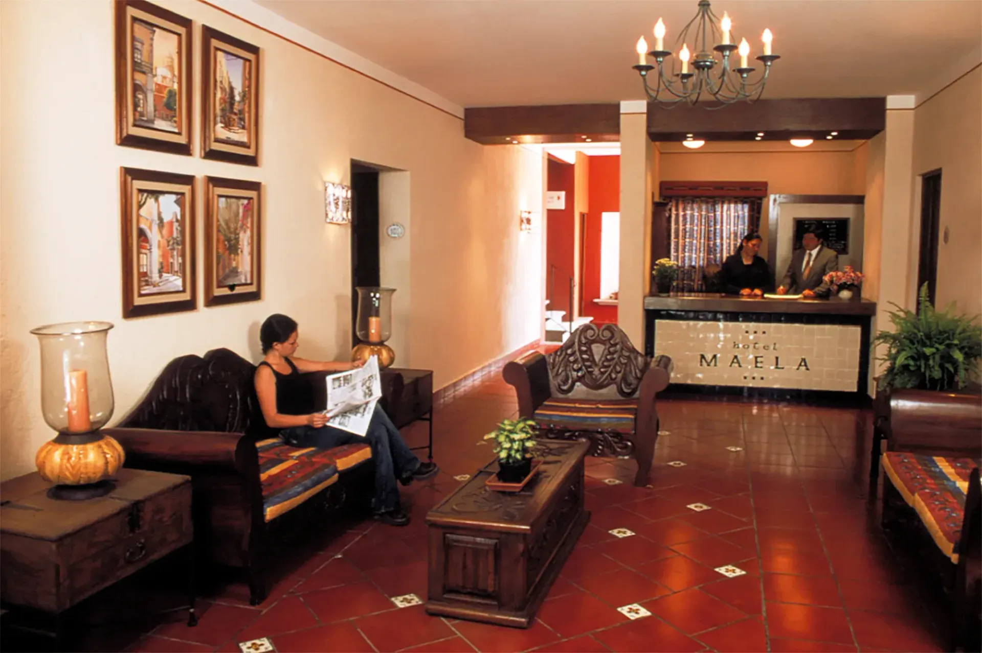 Una persona lee un periódico en el vestíbulo de un hotel con muebles de madera oscura.