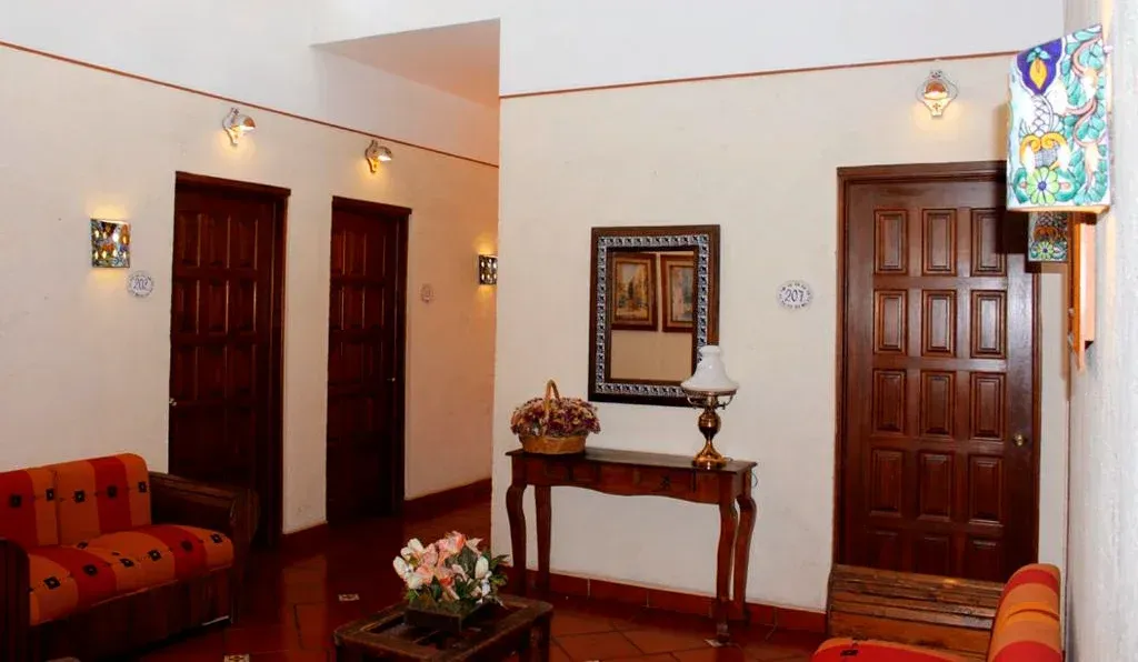Una habitación con un sofá, una mesita auxiliar con lámpara y espejo, y varias puertas de madera.