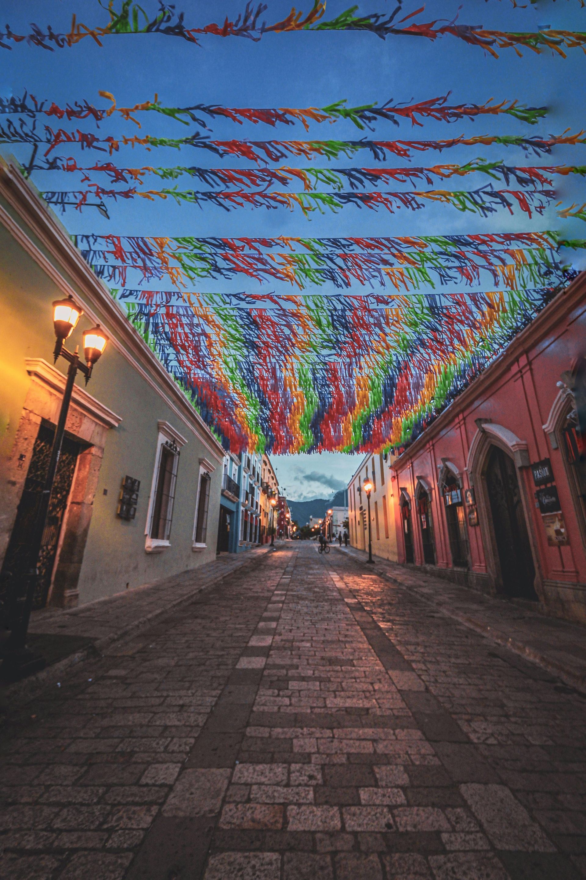 Una estrecha calle empedrada al anochecer, flanqueada por coloridos edificios.