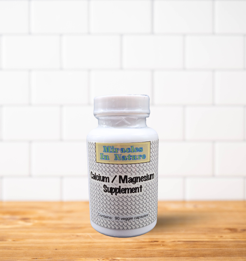 A bottle of calcium and magnesium supplement is sitting on a wooden table.