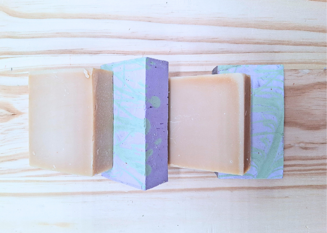 Three bars of soap are stacked on top of each other on a wooden table.