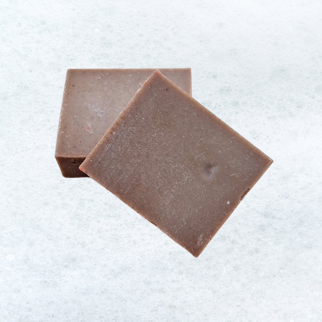 Two squares of chocolate are stacked on top of each other on a white surface.