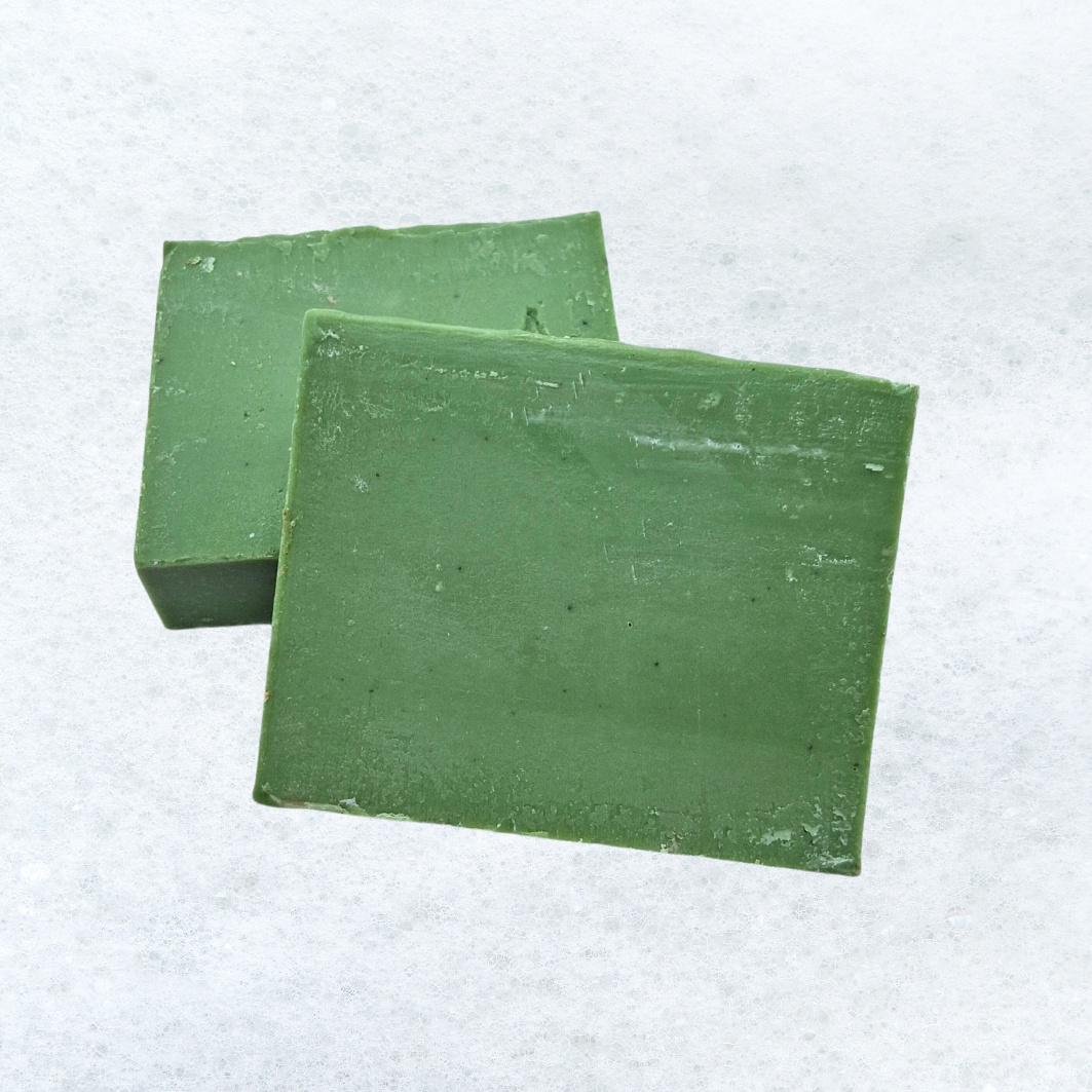 Two green squares of soap are stacked on top of each other on a white surface.