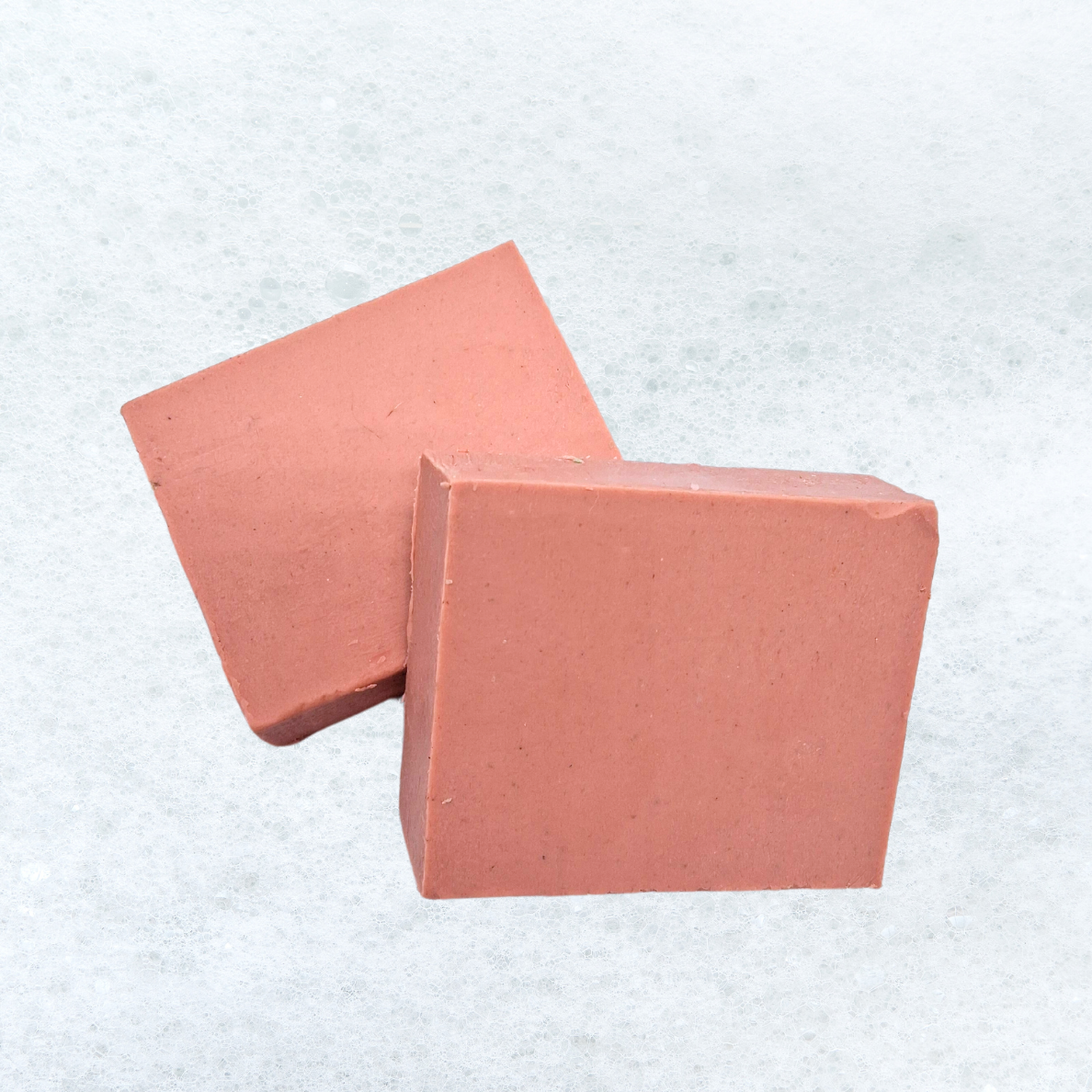 Two pieces of soap are stacked on top of each other on a white surface.