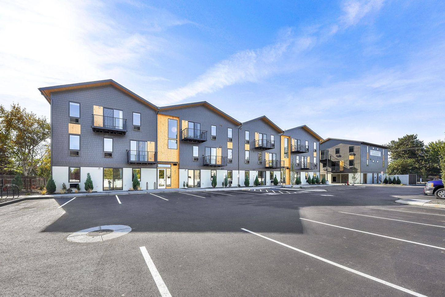 Veazey Park Apartments building with a lot of windows is sitting next to a parking lot.