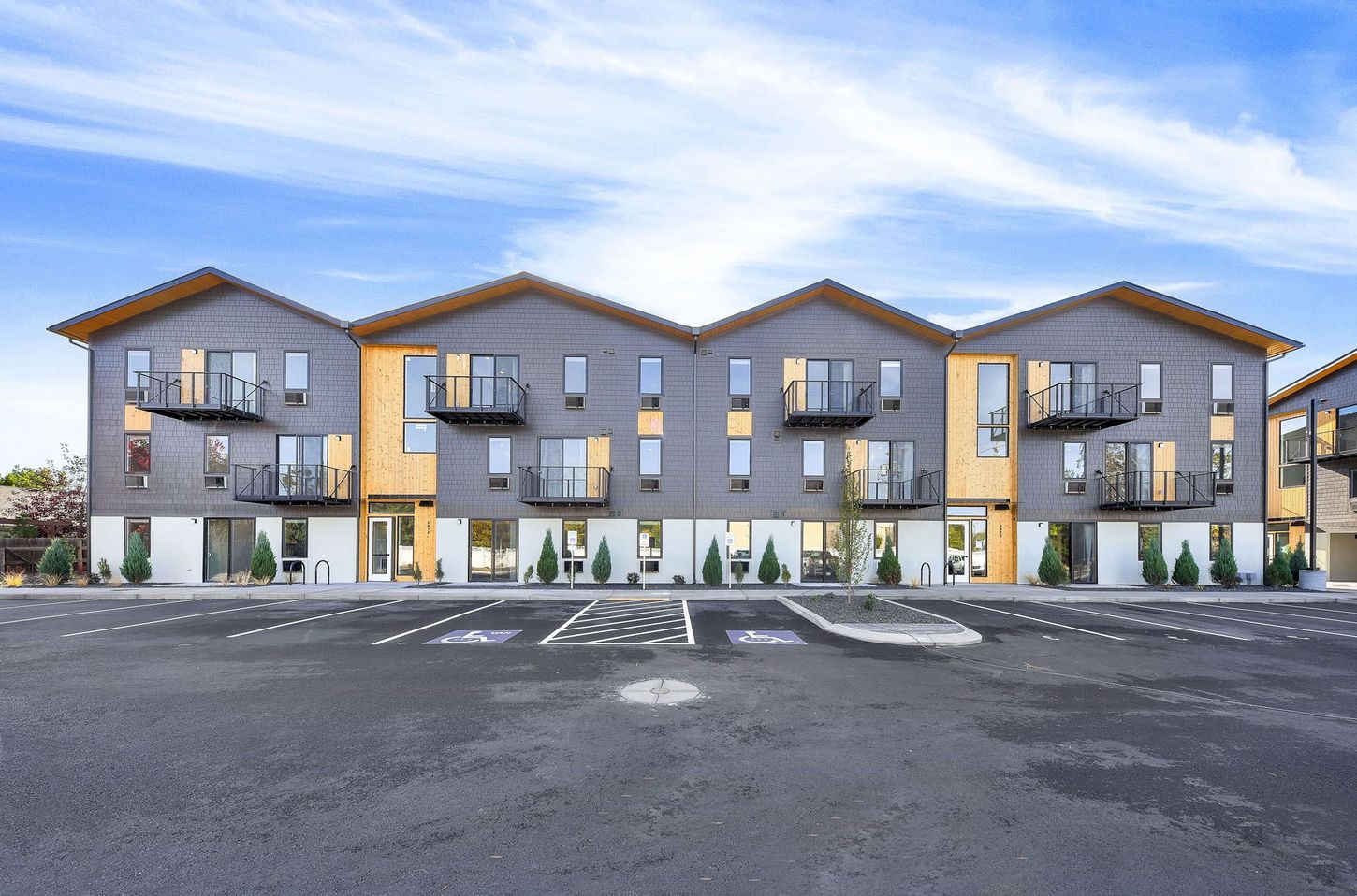 Veazey Park Apartments building with a lot of windows is sitting next to a parking lot.