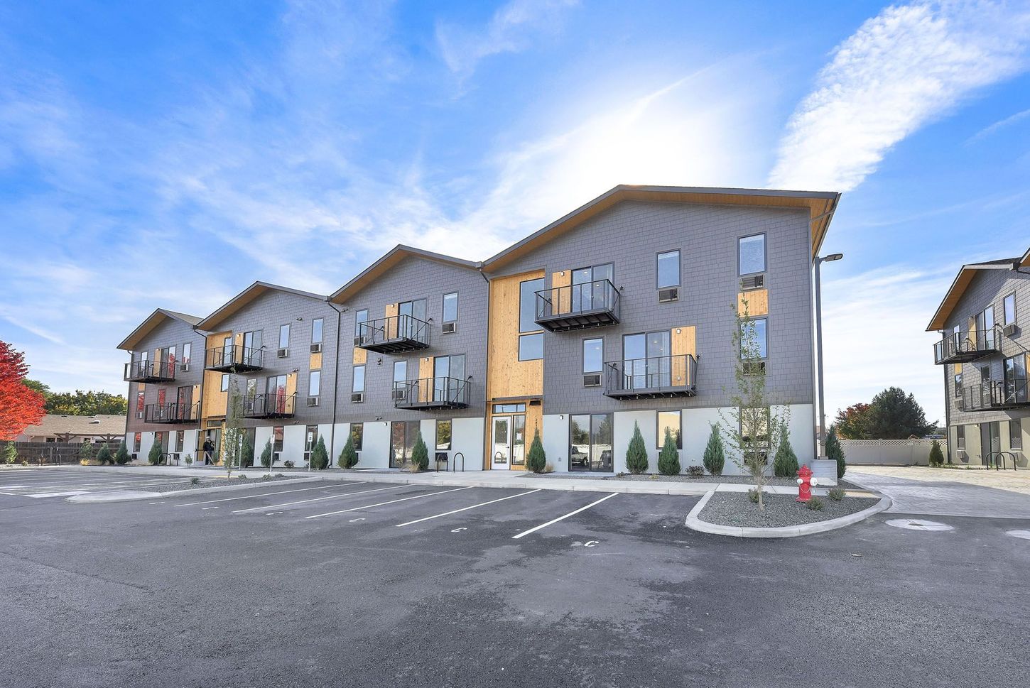 Veazey Park Apartments building with a lot of windows is sitting next to a parking lot.