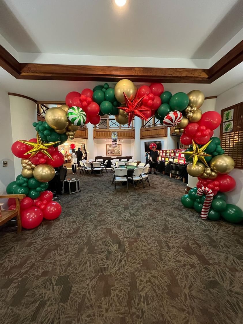A room decorated for christmas with red , green and gold balloons.
