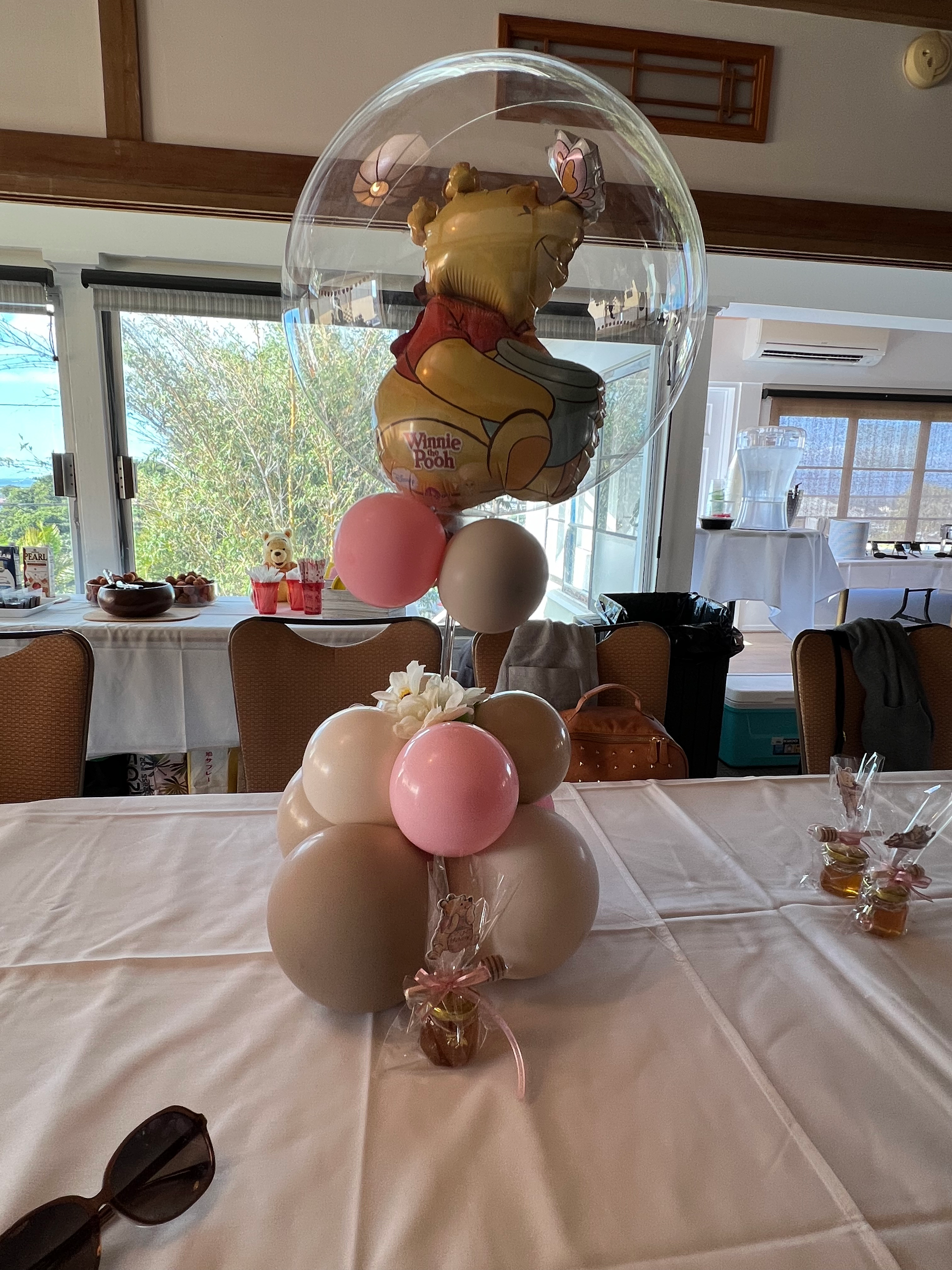 A table topped with balloons and a winnie the pooh balloon.