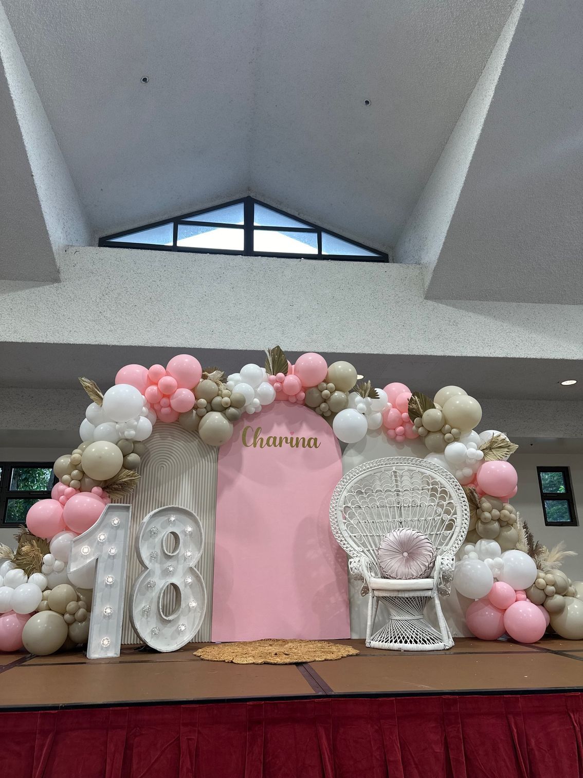 A stage decorated with balloons and a chair for a 18th birthday.
